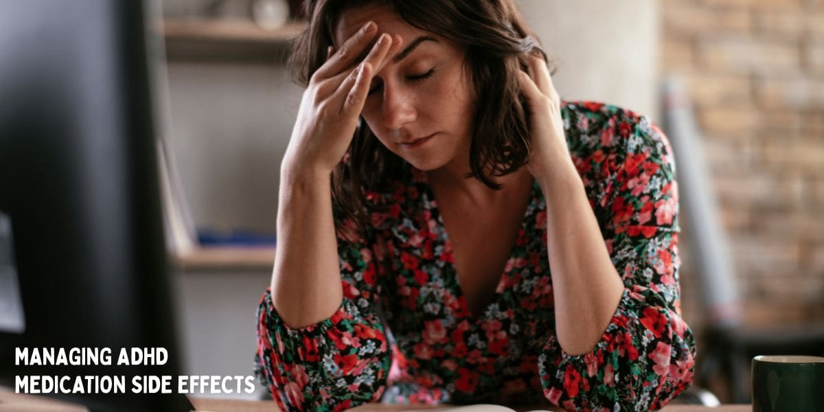 woman holding head at desk, experiencing headache as representation of adhd medication side effect