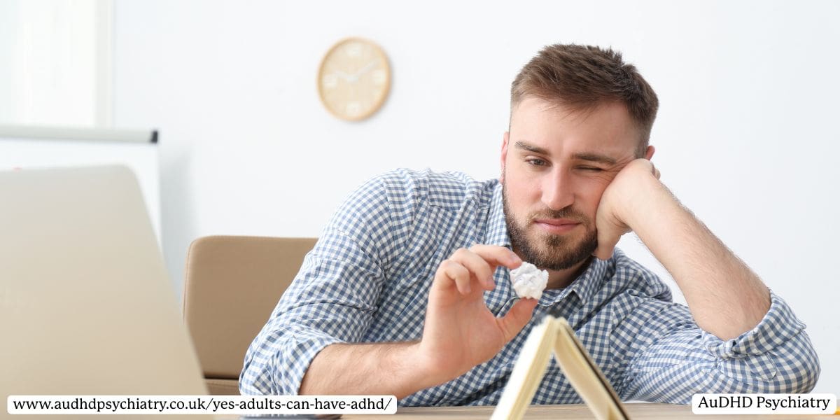 Frustrated adult man sitting at desk with crumpled paper in hand
