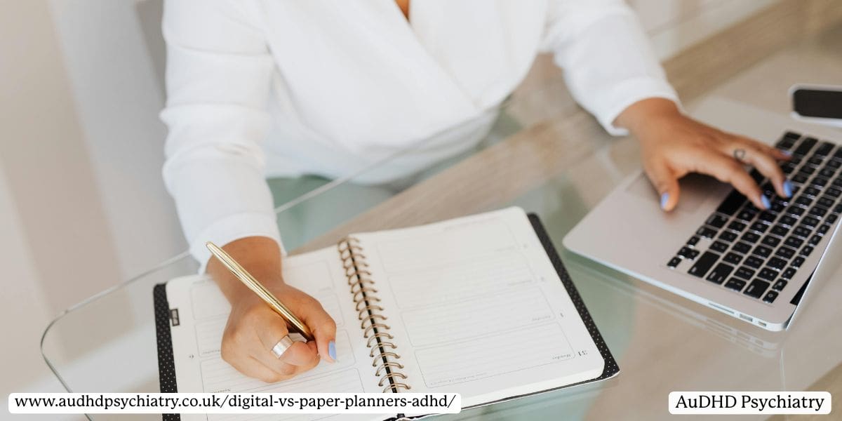 Close-up of hands writing in a minimalist paper planner next to a laptop