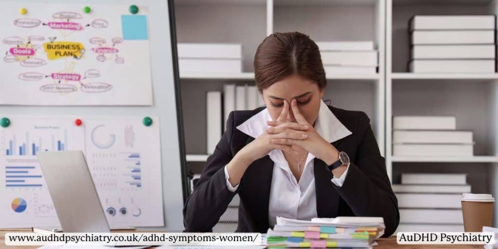 Woman at desk with head in hands – ADHD symptoms women overwhelmed by work stress