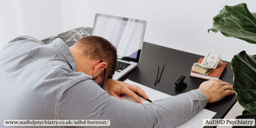 Employee resting head on arms at desk – mental fatigue from ADHD burnout