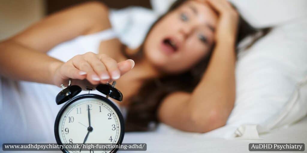 Woman in bed reaching to turn off an alarm clock, showing morning struggles common in high functioning ADHD