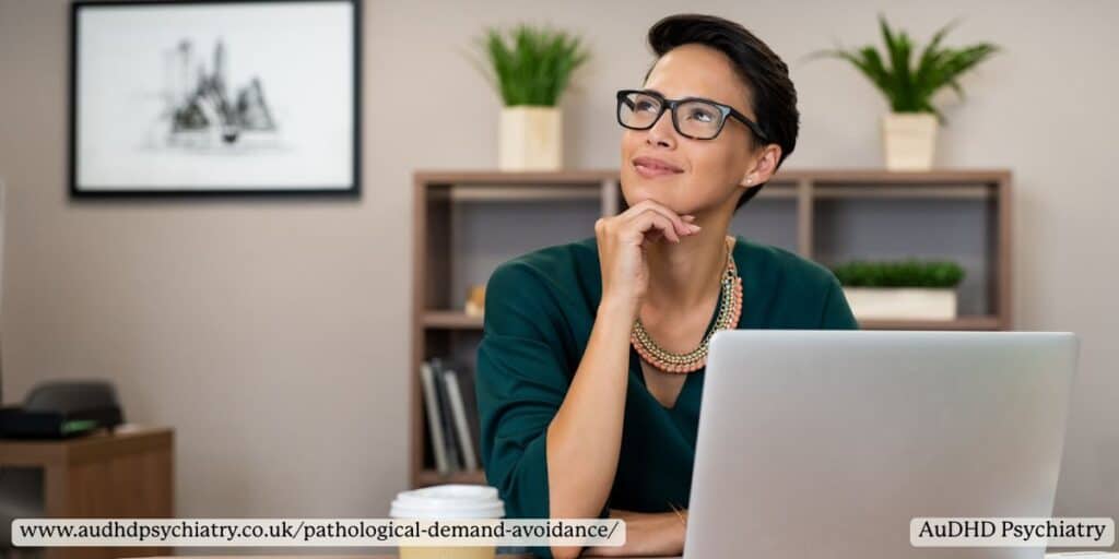 Adult woman sitting at a desk looking thoughtful, reflecting overthinking and anxiety common in pathological demand avoidance