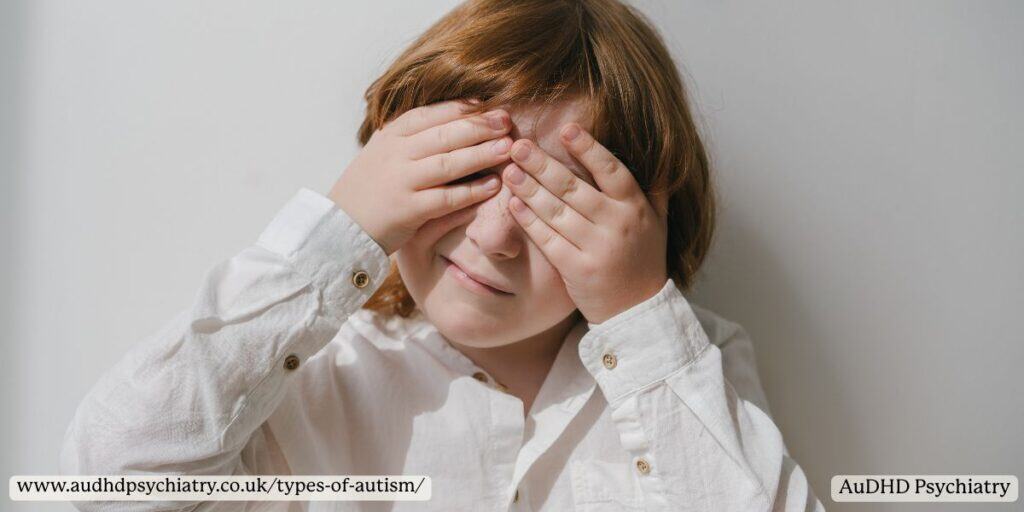 Child in a white shirt covering their eyes due to sensory overload, illustrating behaviours associated with some types of autism