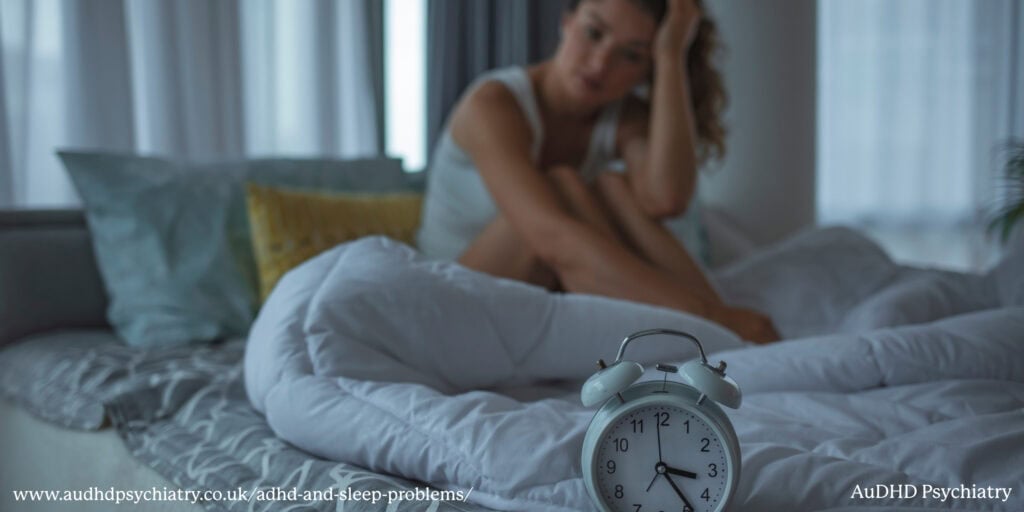 Woman sitting awake in bed next to an alarm clock, representing insomnia linked to ADHD and sleep problems
