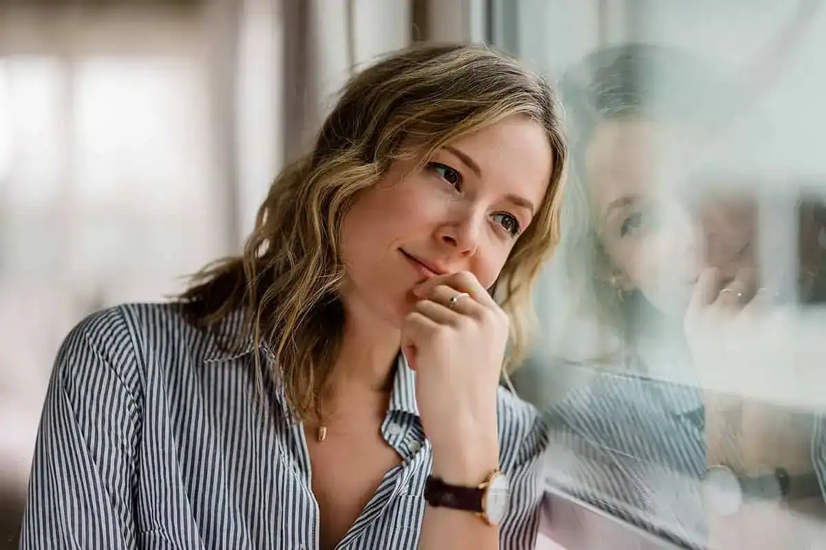 Thoughtful woman looking out of a window at home